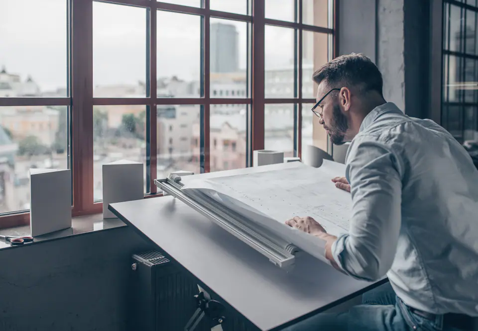 A designer reviewing drawings at a drafting table